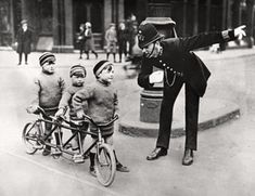 an old photo of a man riding a bike with three small children on the back