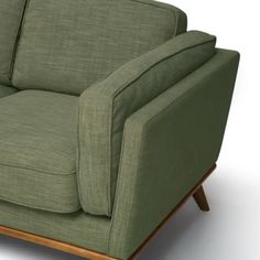 a green couch sitting on top of a white floor next to a wooden leg chair