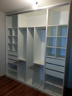 an empty white closet with shelves and drawers on the wall next to a wooden floor