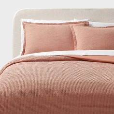 the bed is made with peach colored sheets and pillows