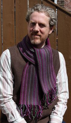 a man with grey hair wearing a purple and black striped knitted scarf over his shoulders