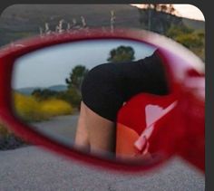 a woman's reflection in the side view mirror of a red and black motorcycle