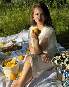 a woman sitting on a blanket with lemons in front of her and baskets full of lemons behind her