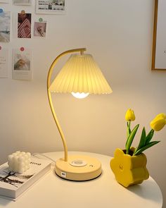 a yellow lamp sitting on top of a table next to a vase with tulips