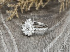 a diamond ring sitting on top of a piece of fabric next to a pine tree