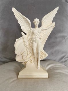 a white angel statue sitting on top of a pillow