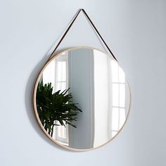 a round mirror hanging on the wall next to a potted plant