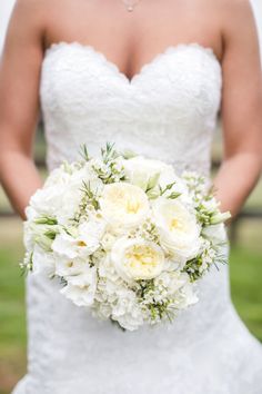 a bride holding a bouquet of white flowers