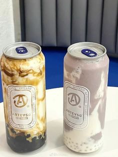 two cans of ice cream sitting on top of a white table next to each other