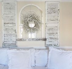 a white couch with pillows and a wreath on the wall