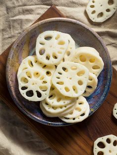 a bowl filled with sliced cheese on top of a wooden cutting board