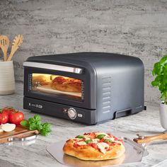 a toaster oven sitting on top of a counter next to a plate with pizza