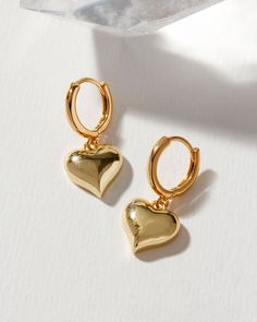 Indulge in the sweet and petite charm of our huggie heart earrings. Their puffy heart charms and effortless clasp closure add a playful touch to your style. Versatility is their superpower – pair them effortlessly with any outfit in your wardrobe. You may find yourself reaching for these delightful earrings time and time again! Huggie Drop Earrings, Everyday Small Hoop Huggie Earrings With Heart Charm, Dainty Heart-shaped Tarnish-resistant Huggie Earrings, Elegant Heart Charm Huggie Earrings, Small Hoop Huggie Earrings With Charms, Gold-plated Huggie Earrings With Charms, Gold Heart Jewelry, Small Earrings Gold, Puffy Heart Charms