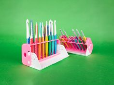 two pink and white toothbrush holders on a green surface with different colored toothbrushes in them