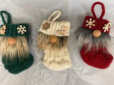 three knitted christmas stocking ornaments on a white sheet