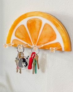 an orange slice hanging on the wall with two keys attached to it and three other key holders in front of it