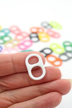 a hand holding a small white object in it's left hand with colorful circles on the background