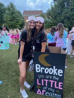 two girls standing next to a sign that says broke you are the little of my dreams