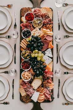 a platter filled with meats, cheeses and fruit on top of a table