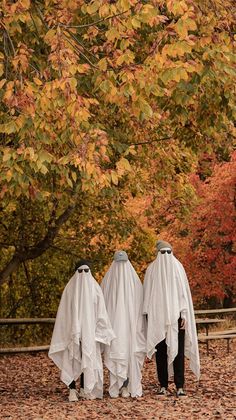 two people dressed in white cloths walking through leaves