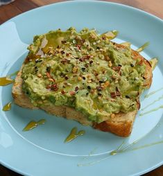 an avocado toast on a blue plate topped with sprinkles and nuts