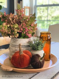 an arrangement of flowers and pumpkins on a plate with honey in a jar next to them