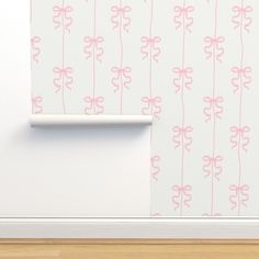 a wall with pink flowers on it next to a white shelf and wooden flooring