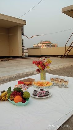 a table topped with plates and bowls filled with fruit on top of a white cloth