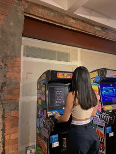 a woman standing in front of an arcade machine