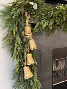 a christmas wreath with bells hanging from it's side next to a fire place