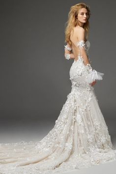 a woman in a wedding dress with flowers on the back and long sleeves, is posing for