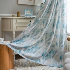 a blue and white curtain hanging from a window next to a desk with a chair