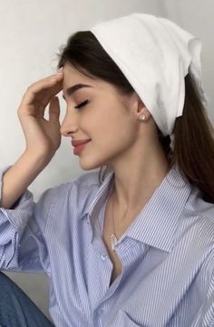 a woman wearing a white headband and blue shirt sitting down with her hands on her hair