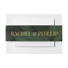 a place card with the name rachel and phillip on it, surrounded by green leaves