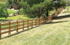 a wooden fence in the middle of a grassy field