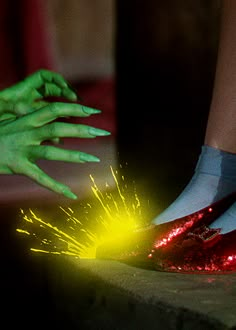 two hands with green and red nail polish on their feet, one holding a sparkler