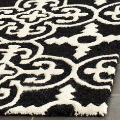 a black and white rug with an ornate design on the bottom, in front of a tile floor