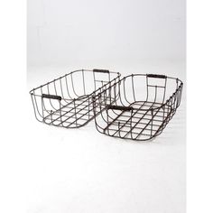 two metal baskets sitting side by side on a white surface