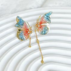 Handmade Pink Blue Butterflies with Drops Earrings These lightweight handmade earrings feature an intricate pink and blue butterfly wing design accented by a drop design. Perfect for a special occasion or everyday wear. As a gift shop, we offer a complimentary gift box for every order. Some details - Size of earring: around 20mm*30mm Materials: Ear stud: gold-plated sterling silver The base of earring: resin The Handmade Pink Blue Butterflies with Drops Earrings are sold on pair of two earrings. About postage: Standard postage When choosing standard postage, we assume this order is for yourself, or you will wrap the item yourself before giving it out as a gift (the complimentary gift box would be posted flat with your order under standard postage). Hence, to be environmentally friendly and Pink And Blue Butterfly, Butterfly Wing Design, Blue Butterfly Wings, Wing Design, Unique Handmade Earrings, Blue Butterflies, Headpiece Jewelry, Bleu Violet, Engagement Ring Box