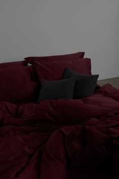 a bed covered in red sheets and pillows