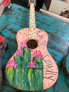 a painted guitar sitting on top of a wooden table