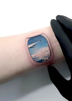 a person with a tattoo on their arm that has an airplane flying above the clouds