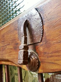 an old wooden door handle with a metal hook on it's side and green wallpaper in the background