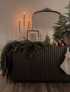 a christmas tree is sitting on top of a dresser next to a mirror and candles