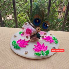 a peacock sitting on top of a white plate with pink flowers and green leaves painted on it