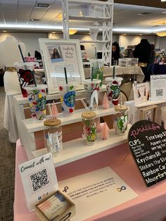 a pink table topped with lots of cards and other items next to a chalkboard sign