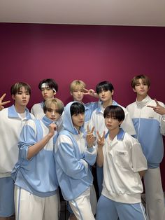 a group of young men standing next to each other in front of a purple wall