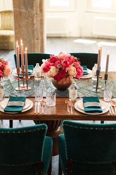 the table is set with candles, plates and vases filled with flowers on it