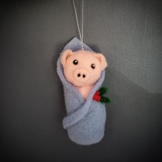 a stuffed animal wrapped in a blanket hanging on a wall with a chain attached to it