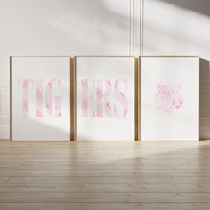 three pink and white art pieces sitting on top of a wooden floor